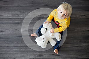 Sweet toddler child, playing doctor, examining teddy bear toy