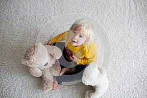 Sweet toddler child, playing doctor, examining teddy bear toy