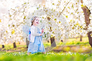 Sweet toddler girl in fairy costume in fruit garden