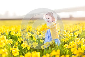 Sweet toddler girl field of yellow daffodil flowers