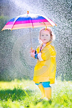 Sweet toddler with umbrella playing in the rain