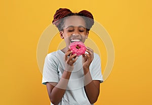 Sweet tooth black girl eating donut on yellow