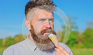 Sweet tooth concept. Bearded man with ice cream cone. Man with beard and mustache on calm face eats ice cream, bite