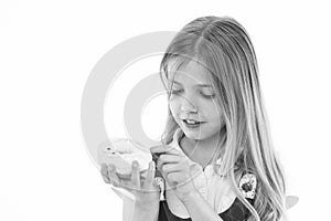 Sweet treasure. Girl calm face carefully holds sweet donut in hand, isolated white. Kid girl with long hair likes donuts