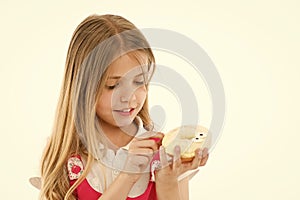 Sweet treasure. Girl calm face carefully holds sweet donut in hand, isolated white. Kid girl with long hair likes donuts