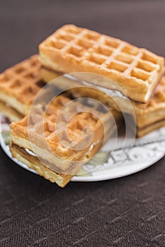 Sweet Viennese waffles with white filling lie on a saucer