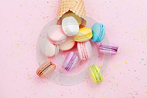 Sweet waffle cone with macaron or macaroon on pink pastel background top view. Flat lay composition. photo
