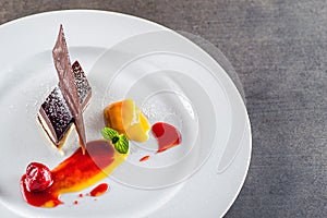 Sweet white-brown chocolate dessert with fruits, decoration and mint leaf on white plate, product photography for patisserie or re