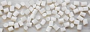 Sweet white marshmallows on a white wooden table, overhead view. Flat lay, from above, top view. Close-up view. Close-up