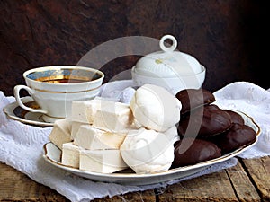 Sweet white Russian marshmallow, chocolate zephyr, meringue, apple pastila and cup of coffee on wooden background.