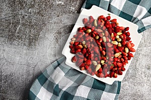 Sweet wild strawberries (Fragaria vesca) on a white square plate on a dark background