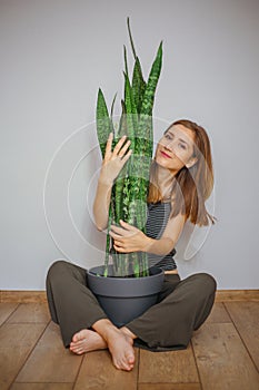 Sweet young blonde girl with Sansevieria plant.