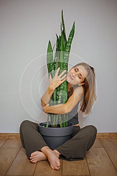 Sweet young blonde girl with Sansevieria plant.