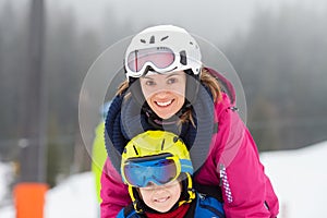 Sweet young boy and his mother, learning to ski on a mild ski slope in Austrian ski resort