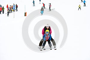 Sweet young boy and his mother, learning to ski on a mild ski slope in Austrian ski resort