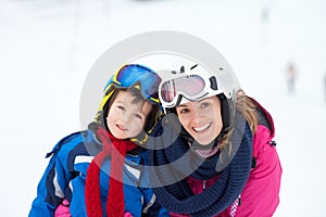 Sweet young boy and his mother, learning to ski on a mild ski slope in Austrian ski resort