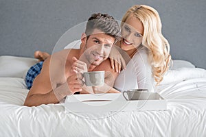 Sweet Young Caucasian Lovers on Bed Having Coffee