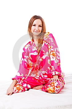 Sweet young girl in pink pajamas on bed