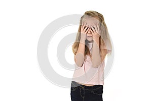 Sweet young little schoolgirl covering her face with her hands crying sad victim of bullying at school