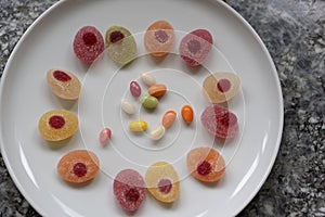 Sweeties for easter. Easter candies in a circle on a white plate on a gray granite table