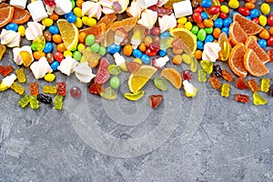 Sweets and candies background. Different candies, marshmallows, marmalade, yummi gummi scattered on the table. photo