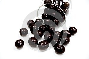 Sweets that are coated with chocolate scattered from clear glass cups. Colorful candies background top view.