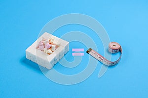 Sweets and measuring tape on a blue background. The concept of obesity from the frequent consumption of sweets