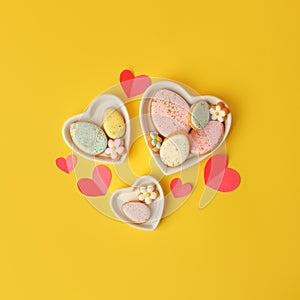 Sweets, pastry, gingerbread cookies for Easter table. Easter eggs heart shaped decor  on yellow background top view copy space,