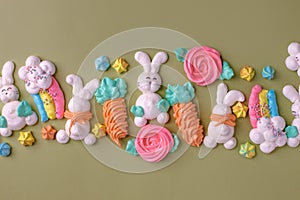 Sweets, pastry, gingerbread cookies for Easter table. Easter rabbit bunny, tender rainbow on green background top view copy space