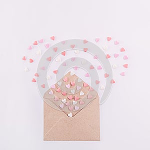 Sweets sugar candy hearts fly out in the form of heart from craft paper envelope on the white background . Valentine day concept.