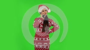 Sweety girl in Santa Claus hat is angrily talking for mobile phone. Green screen