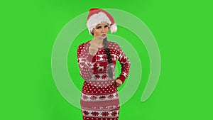 Sweety girl in Santa Claus hat threatens with a fist. Green screen