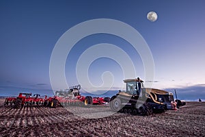 Swift Current, SK/Canada- 10 May, 2019: Full moon over Caterpillar tractor and Bourgault air drill in the field