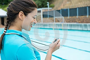 Swim coach looking at stop watch near poolside