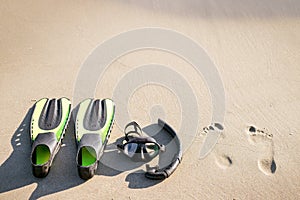 Swim flippers with snorkel, mask and feet steps on a sandy beach. Water sports. Snorkeling. Travel and holiday concept. Fins and s