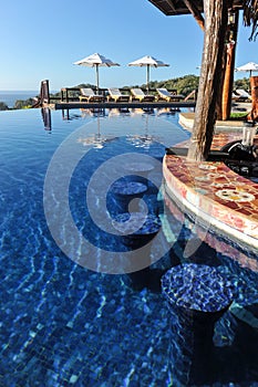 Swim-up bar in infinity pool in tropics