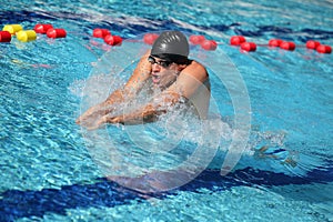 Swimmer in cap breathing performing the breaststroke