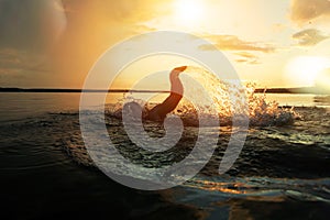 Swimmer conducts training in a lake at sunset after the rain. From under hands fly spray