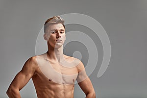 Swimmer on a gray background, hands on the belt, copy space, gray background, young swimmer with a perfect body.