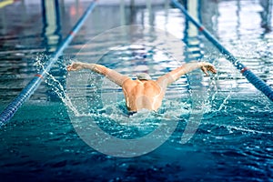 Swimmer performing the butterfly stroke at indoor swimming competition