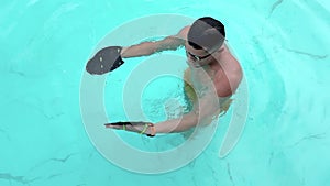 Swimmer. Professional swimmer prepares for competitions in the pool. Young athletic man wearing swimming goggles and mad