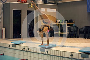 Swimmer, that ready to jump into indoor sport swimming pool. standing on arms with legs up