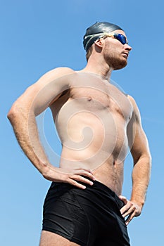 Swimmer with swimming goggles posing with blue sky