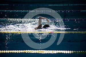 Swimmer swims freestyle in the pool in beautiful sunlight