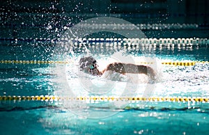 Swimmer swims freestyle in the pool in beautiful sunlight