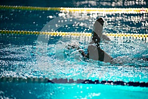 Swimmer swims freestyle in the pool in beautiful sunlight