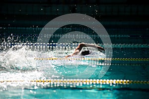 Swimmer swims freestyle in the pool in beautiful sunlight