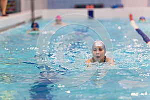 Swimmer young girl breathing performing the butterfly stroke in swimming pool, copy space