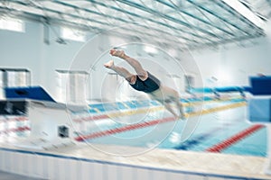 Swimming, action and man diving in pool for training, exercise and workout for competition at gym. Fitness, sports and