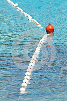 Swimming area barrier buoy rope floating on the turquoise colored sea